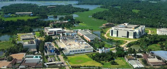 Aerial view of a large Square Pharmaceuticals campus of white buildings surrounded by water and green fields.